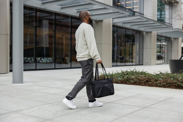 A person carrying a Nomad Tote by the handles.